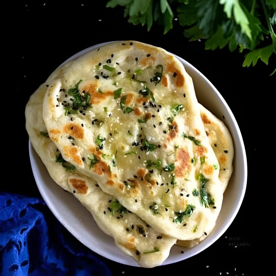 A white bowl filled with Wok & Sizzle's Indian naan bread, topped with herbs and sesame seeds.